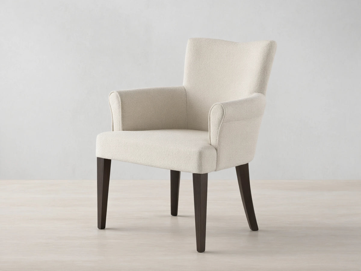 Front view of the cream upholstered Giovanni Dining Arm Chair with dark brown tapered wood legs.