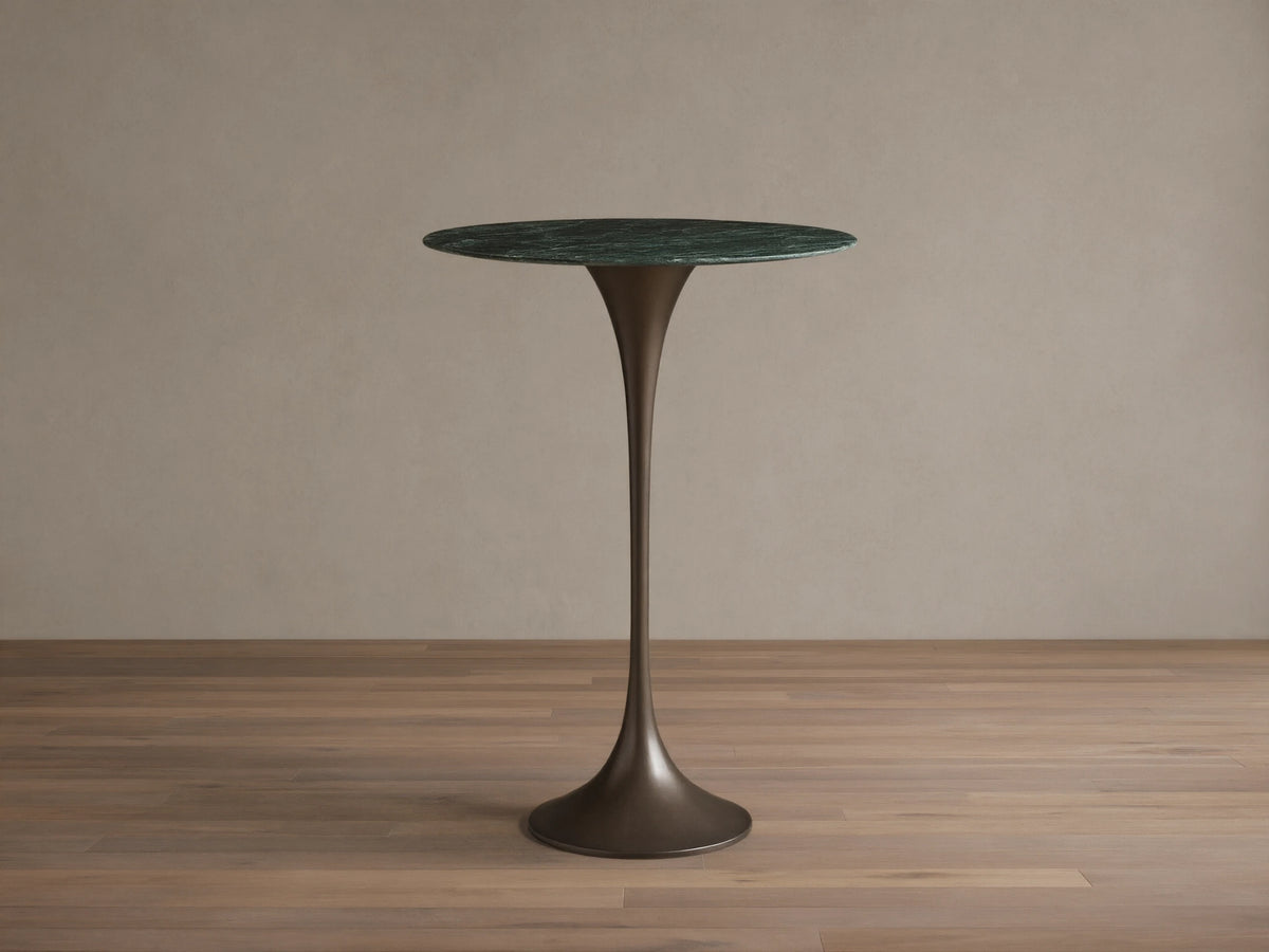 Front view of the Saint Germain Bar Table with a round dark green natural stone top and a dark bronze trumpet-shaped steel base.