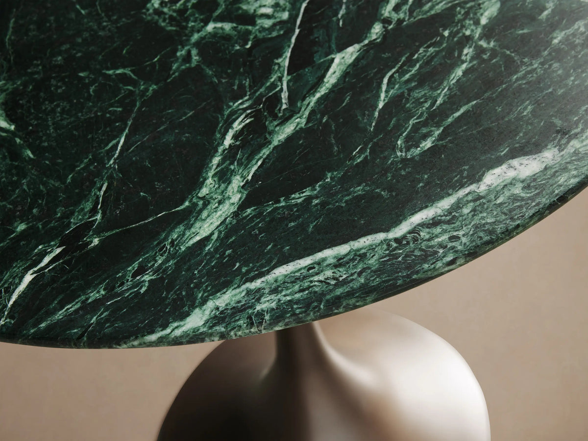 Front view of the Saint Germain Bar Table with a round dark green natural stone top and a dark bronze trumpet-shaped steel base.