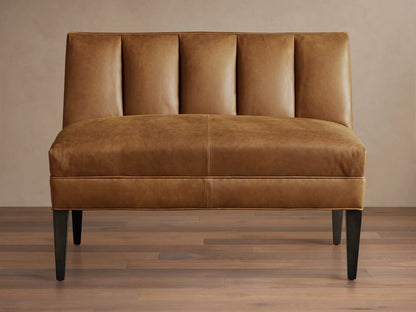 Gates Leather Bench, tan brown, front view. Channel-stitched back, flat seat, dark tapered legs on wood floor.