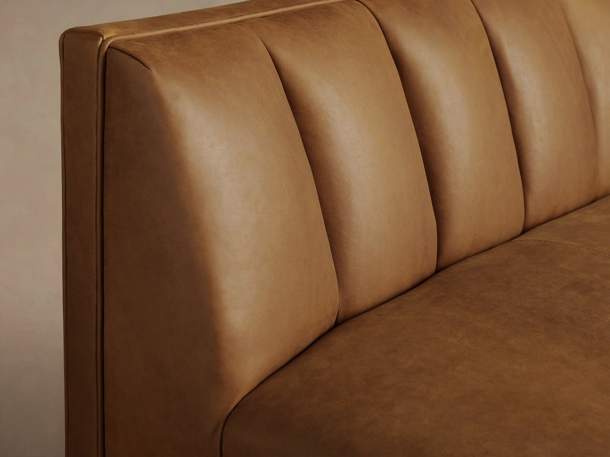 Gates Leather Bench, warm brown leather with channel-stitched backrest, square seat, and dark tapered legs on wood floor.