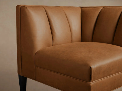 Tan Gates Leather Corner chair with a channel-stitched back in warm brown leather, featuring dark tapered legs on a wood floor.