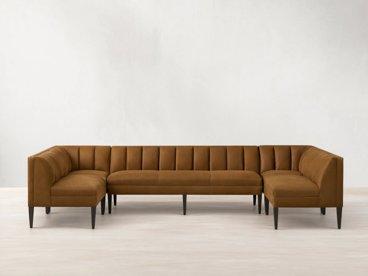 Gates Leather U-Shaped Banquette, rich brown, channel-stitched backrests, dark tapered legs on a wooden floor.