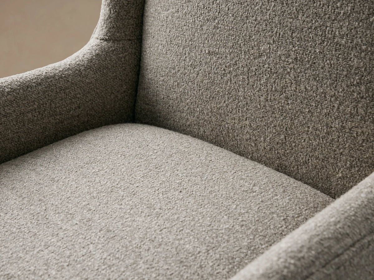 Halstead Dining Chair with high backrest, curved armrests, and textured gray upholstery on dark wood legs, set on a wooden floor.