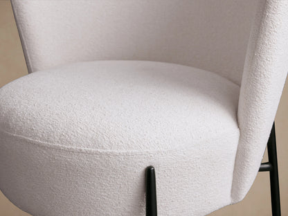 A Hanne Dining Captain Chair with a white curved backrest, cushioned seat, and black powder-coated metal legs on a wooden floor.