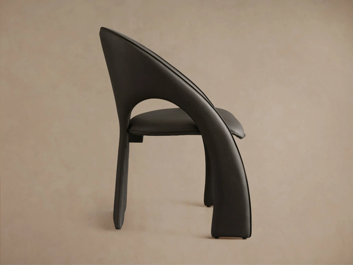 Front-side view of a dark grey Hearst Dining Side Chair, featuring a sculptural, curved back and upholstered seat.
