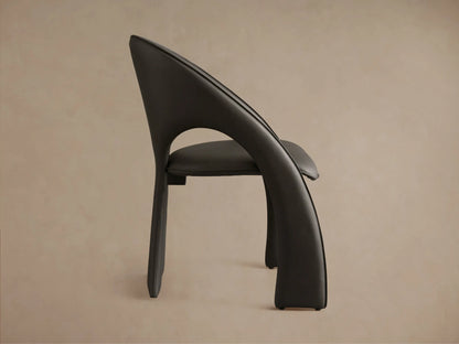 Front-side view of a dark grey Hearst Dining Side Chair, featuring a sculptural, curved back and upholstered seat.