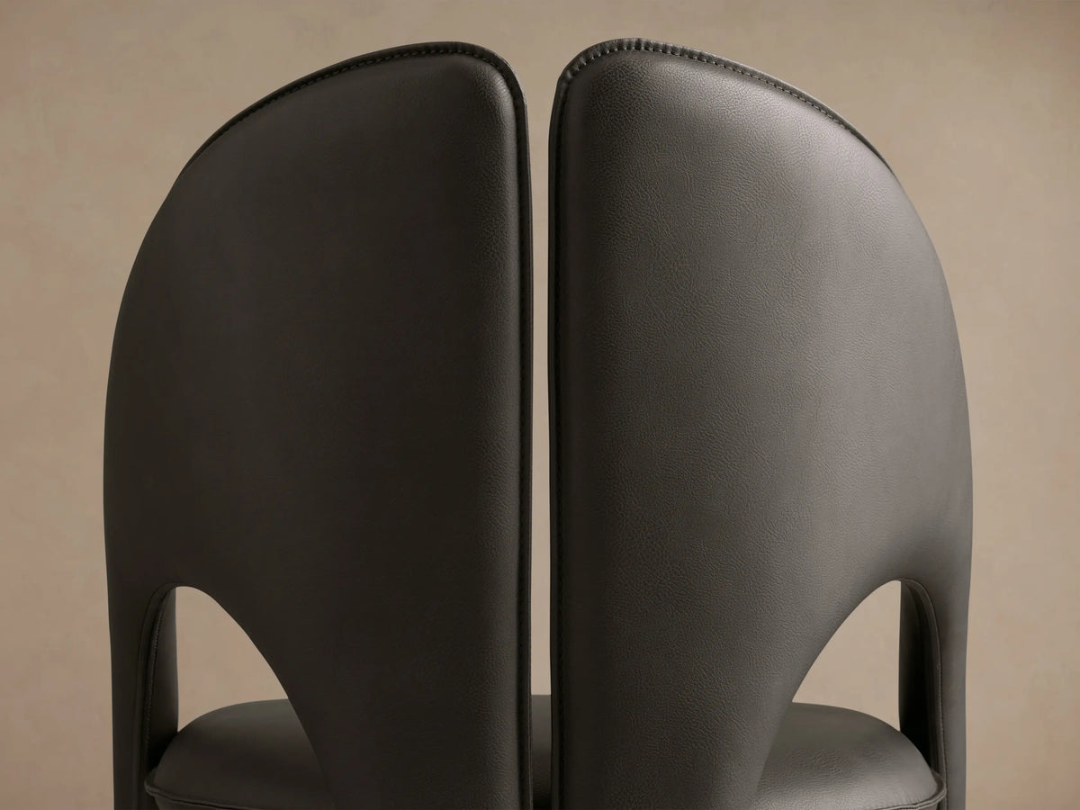 Side profile of the dark gray Hearst Dining Side Chair, showing its sculptural curved back and upholstered seat.
