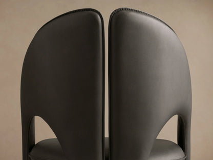 Side profile of the dark gray Hearst Dining Side Chair, showing its sculptural curved back and upholstered seat.