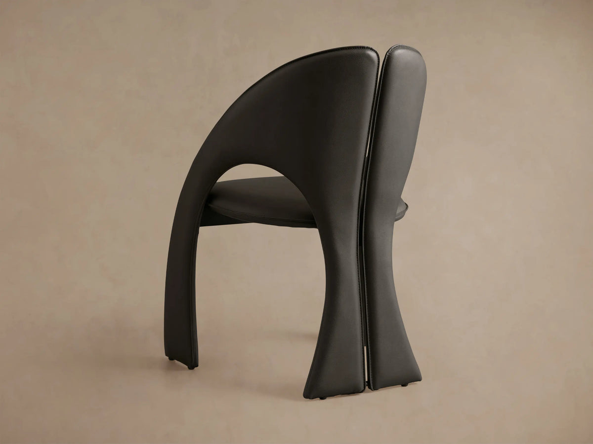 Rear view of two dark grey Hearst Dining Side Chairs with curved backrests, visible stitching, and lower cutouts.