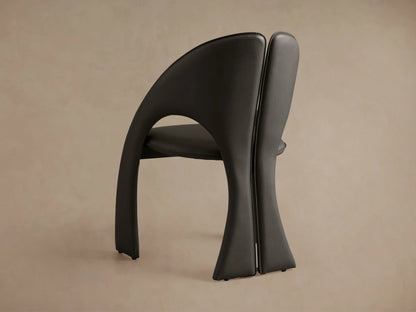 Rear view of two dark grey Hearst Dining Side Chairs with curved backrests, visible stitching, and lower cutouts.
