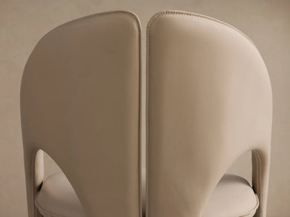 Rear view of two cream Hearst Dining Side Chairs, showing curved backs with visible topstitching detail.