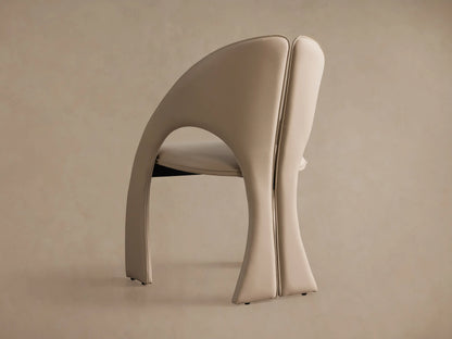 Side profile of the beige Hearst Dining Side Chair with its distinctive curved back, split backrest, and sculptural legs.