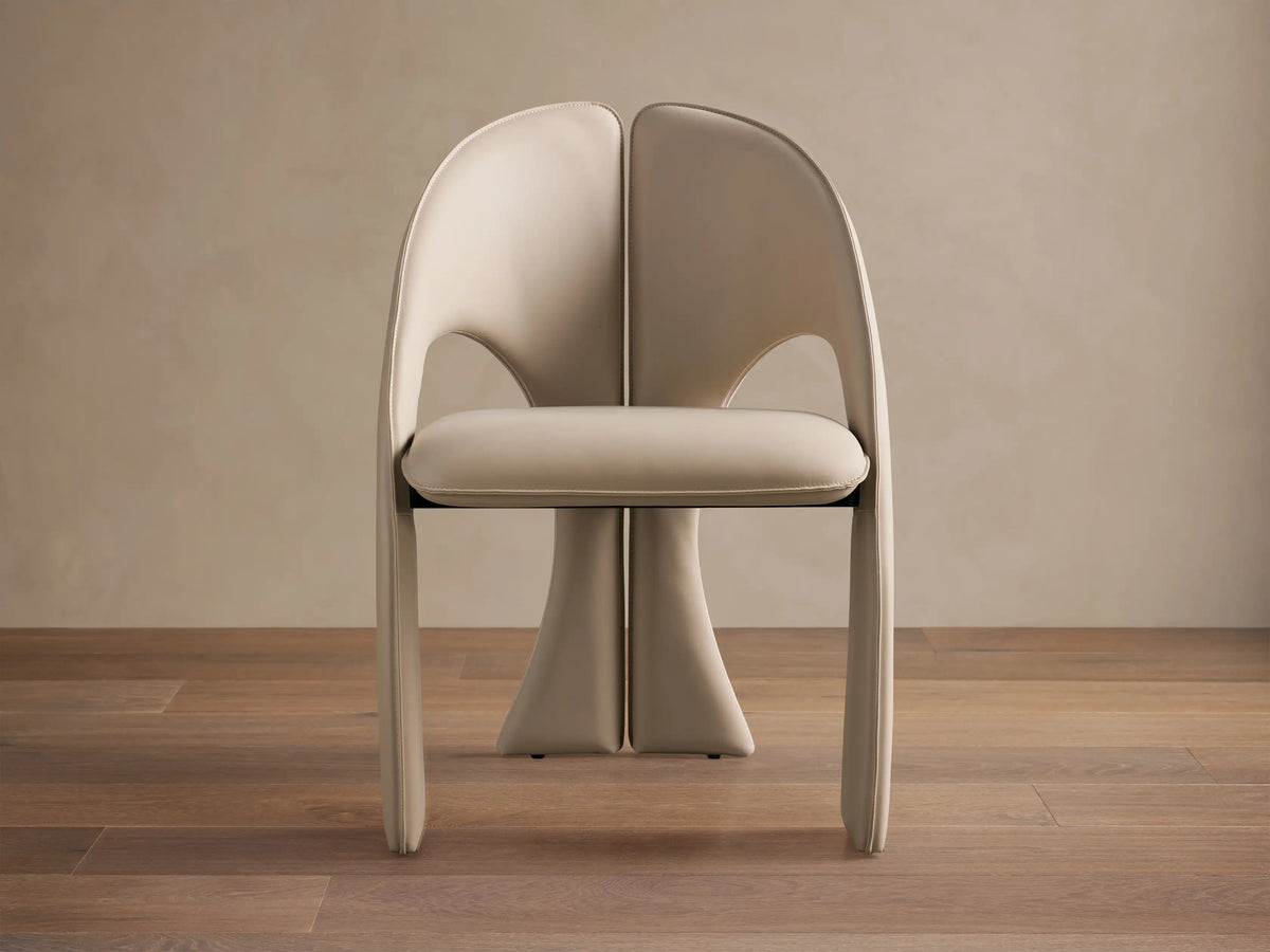 Front view of the cream Hearst Dining Side Chair, fully upholstered with a distinctive split-back design and integrated curved legs.