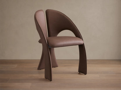 Front view of the brown Hearst Dining Chair, featuring a unique curved upholstered backrest and seat, and distinctive leg design.