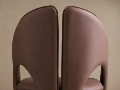 Front view of the brown Hearst Dining Chair, with a distinctive split, curved backrest and upholstered legs.