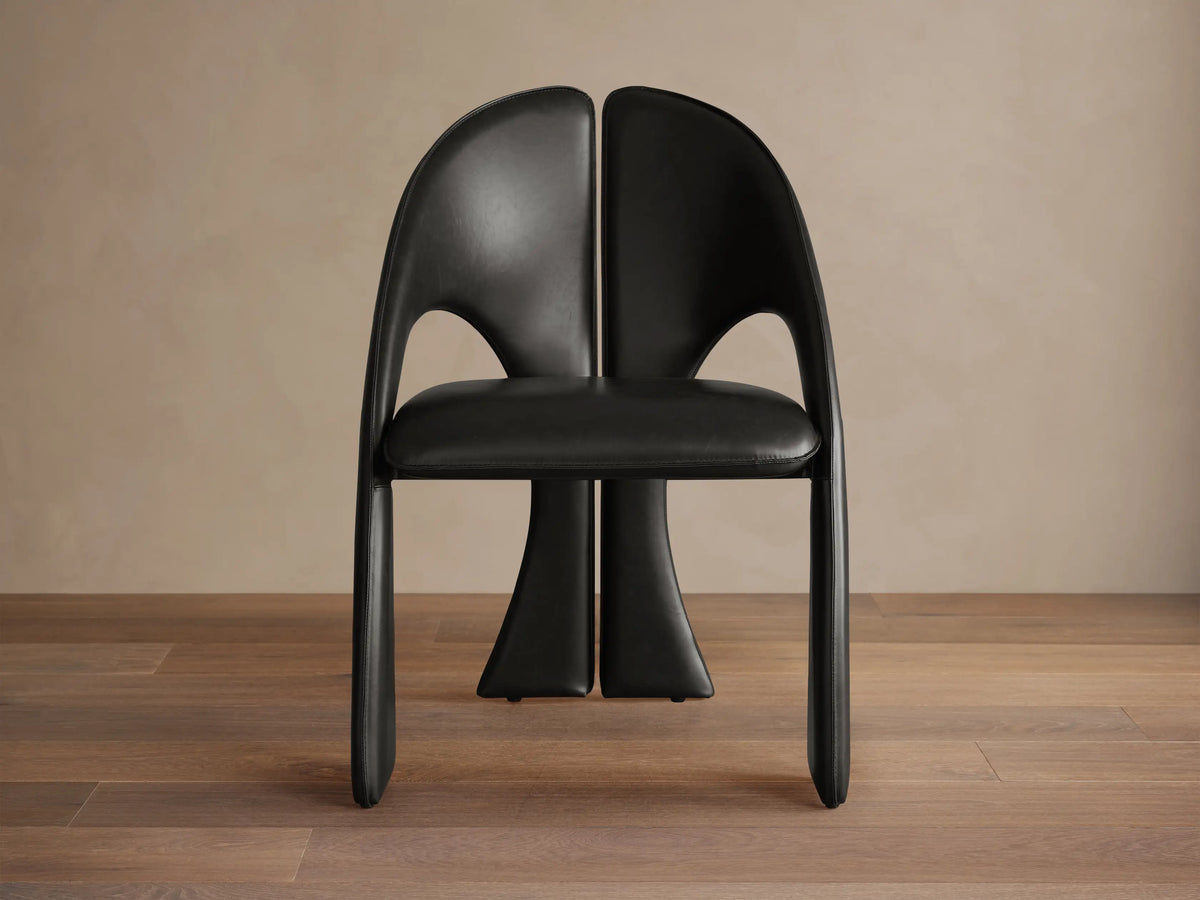 Front view of the Black Hearst Dining Side Chair, featuring a curved, split upholstered back and upholstered legs.