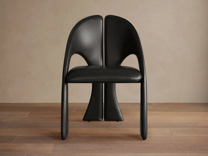 Front view of the Black Hearst Dining Side Chair, featuring a curved, split upholstered back and upholstered legs.