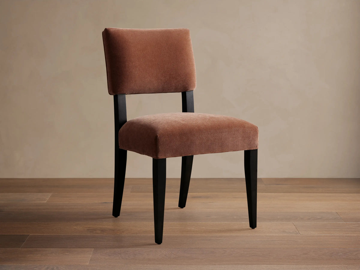 Hartley Dining Chair with rust velvet upholstery, dark tapered & splayed legs, angled on wood floor.