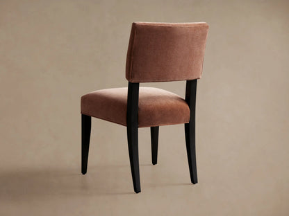 Hartley Dining Chair: close-up of salmon-colored velvet upholstered backrest and seat on a dark wood frame.
