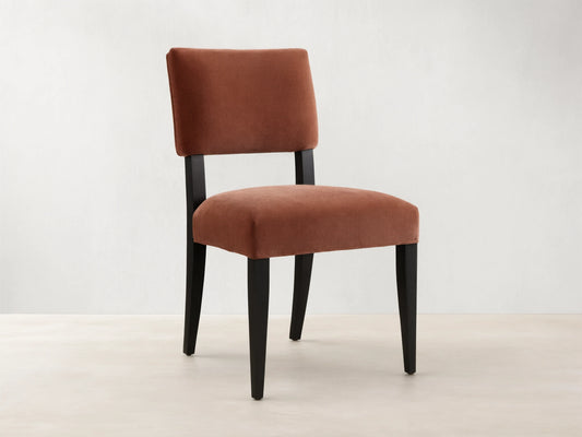 Hartley Dining Chair with rust velvet upholstery, dark tapered & splayed legs, angled on wood floor.
