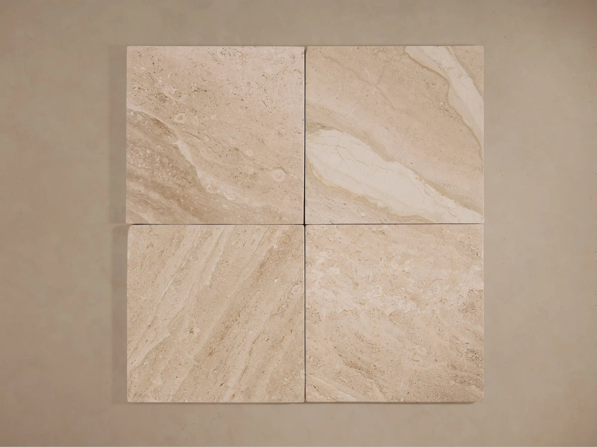 Four square slabs of beige coralle marble with varying natural patterns and textures, aligned in a grid.