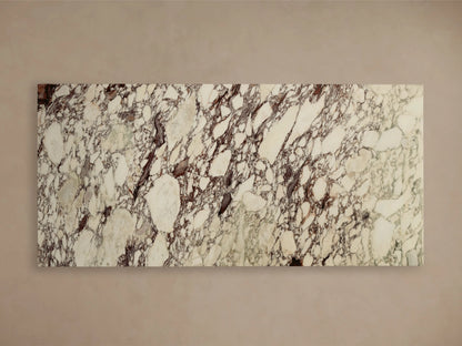 Close-up of the natural stone surface of the Ilaria Dining Table, showing cream and white with dark brown and purplish veining.