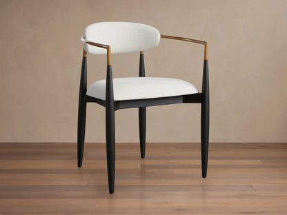 Jagger Dining Arm Chair with white cushioned seat and backrest, black slender legs, and wooden armrests on a wooden floor.
