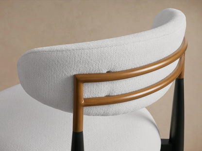 Jagger Armless Stool with white cushioned seat and backrest, black legs, on wooden floor, against a neutral wall.