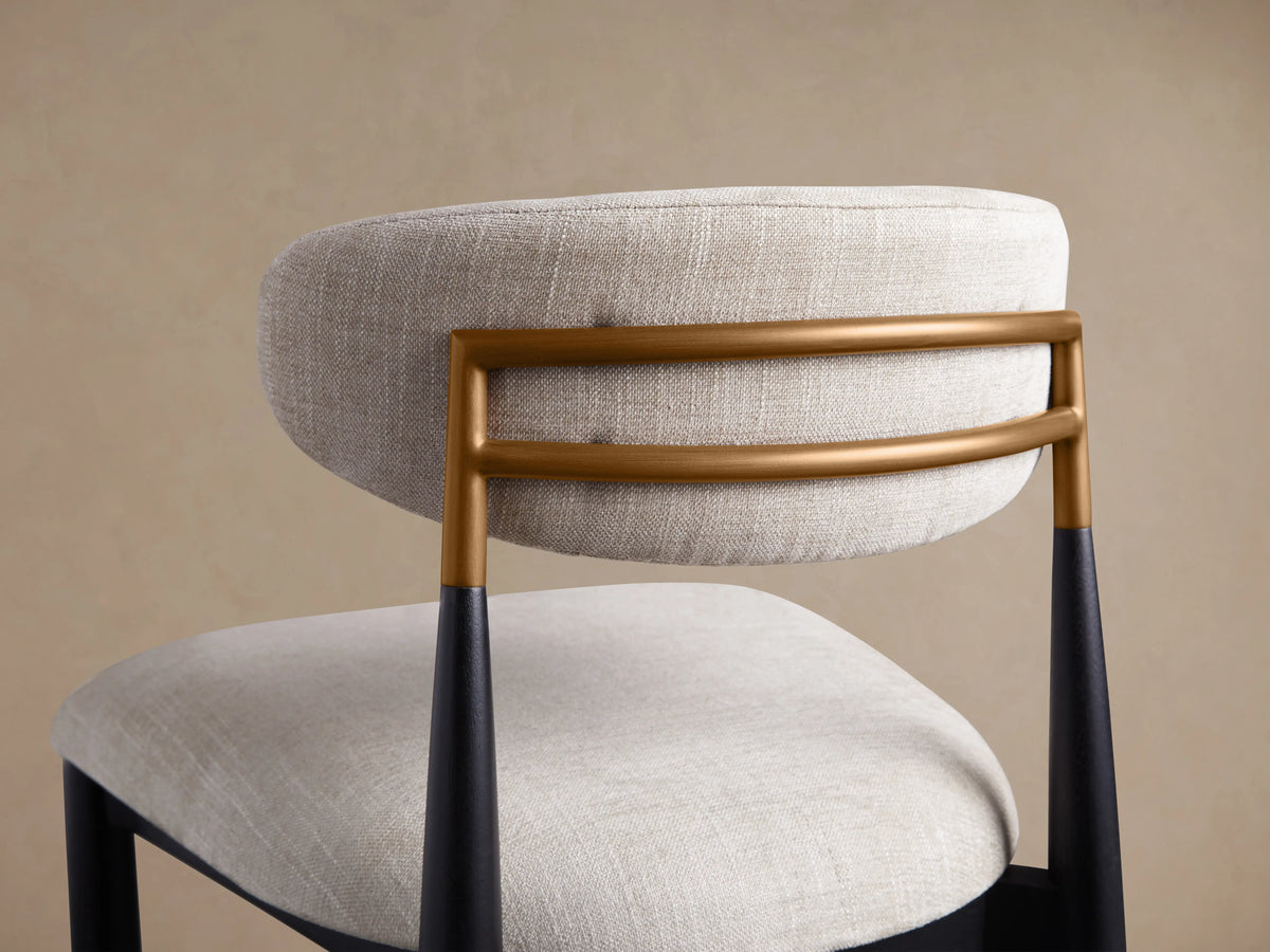 Jagger Dining Side Chair, close-up of light beige linen-look back & seat, with brass bars & black tapered rear legs.