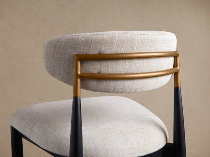 Jagger Dining Side Chair, close-up of light beige linen-look back & seat, with brass bars & black tapered rear legs.