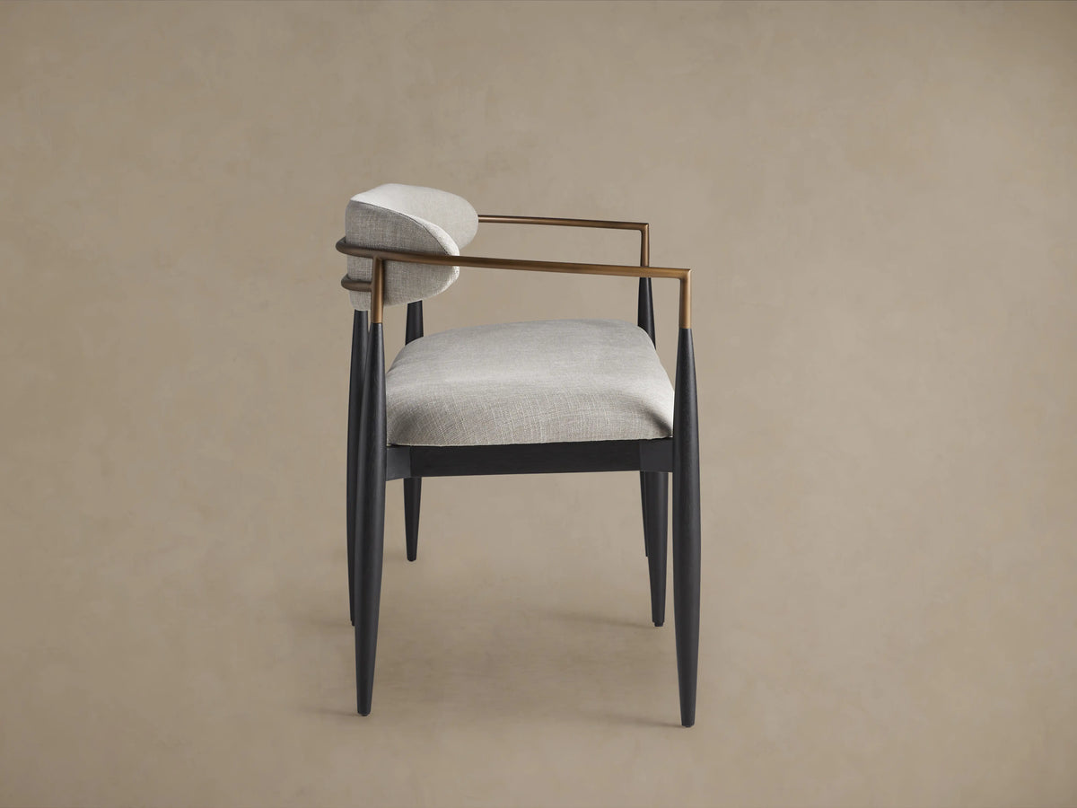 Jagger Dining Bench with a sleek design features light grey cushioned seating and backrest, black legs and arm supports, on wooden floor.