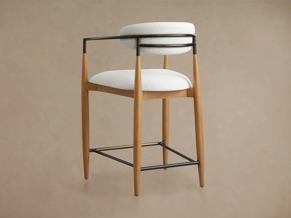 Jagger Stool featuring a wooden frame with a clear lacquer finish, cushioned white seat and backrest, and sleek black metal supports.