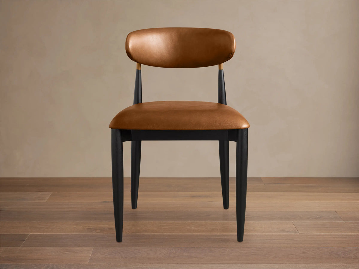 Jagger Faux Leather Dining Side Chair: Tan faux leather seat & back, sleek black frame with brass detail, on wood floor.