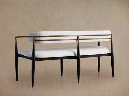 Jagger Dining Bench with white cushioned seat and backrest, black legs, and bronze accents, against a neutral background.