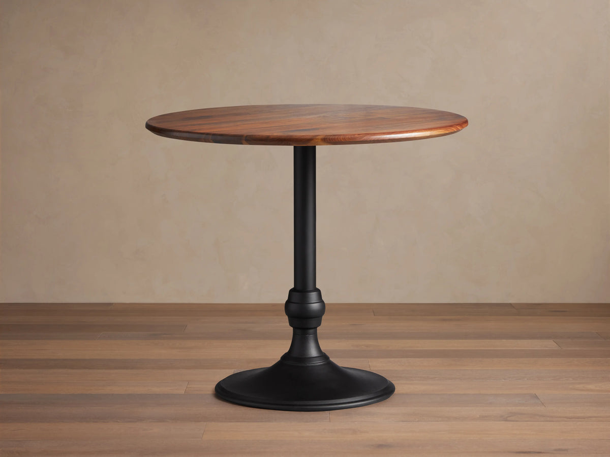Jacob Counter Table with Wade Base showing a round solid walnut top and a black iron base on wooden floor.
