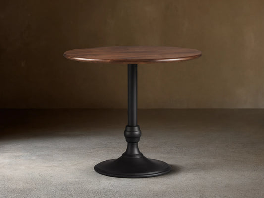 Jacob Counter Table with Wade Base showing a round solid walnut top and a black iron base on wooden floor.