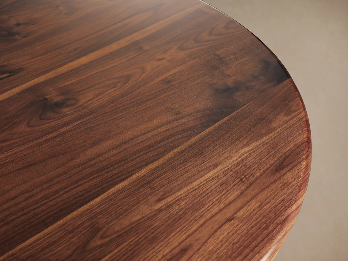 Jacob Bistro Table with a warm walnut round tabletop, supported by an elegant brass-finished Wade Base on a wooden floor.