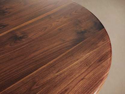 Jacob Bistro Table with a warm walnut round tabletop, supported by an elegant brass-finished Wade Base on a wooden floor.