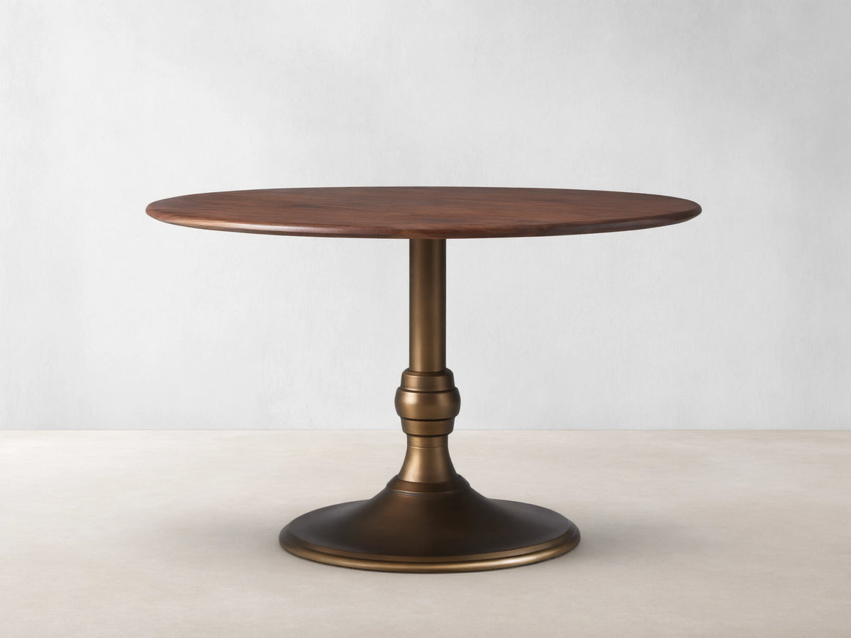 Jacob Bistro Table with a warm walnut round tabletop, supported by an elegant brass-finished Wade Base on a wooden floor.