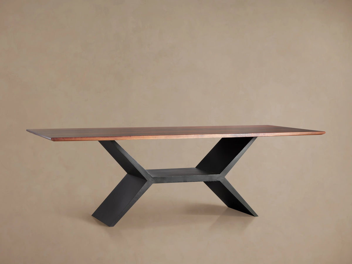 Jacob Dining Table with a rectangular brown walnut wood top on a dark, geometric vertex base, centered against a beige wall.