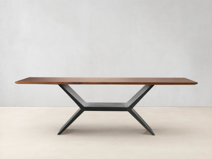 Jacob Dining Table with a rectangular brown walnut wood top on a dark, geometric vertex base, centered against a beige wall.