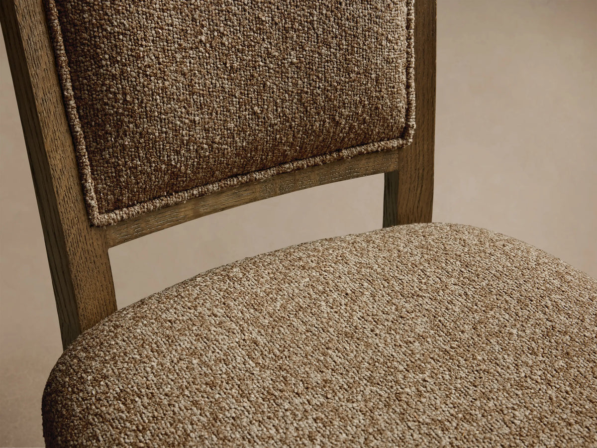 Front view of the Jeannine Upholstered Camel Back Dining Side Chair, with textured beige upholstery and an oak frame.