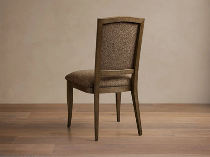 Close-up of the light brown textured upholstery and visible oak frame on the Jeannine Upholstered Camel Back Dining Side Chair.