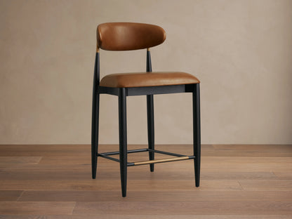 Jagger Faux Leather Armless Stool with brown faux leather seat and backrest, black frame and legs, on wooden floor.