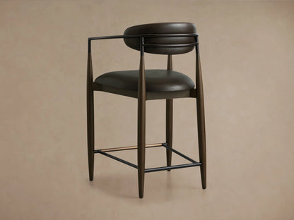 Jagger Faux Leather Stool featuring a dark brown faux leather seat and backrest with a curved design, supported by sleek dark metal and tapered wooden legs.