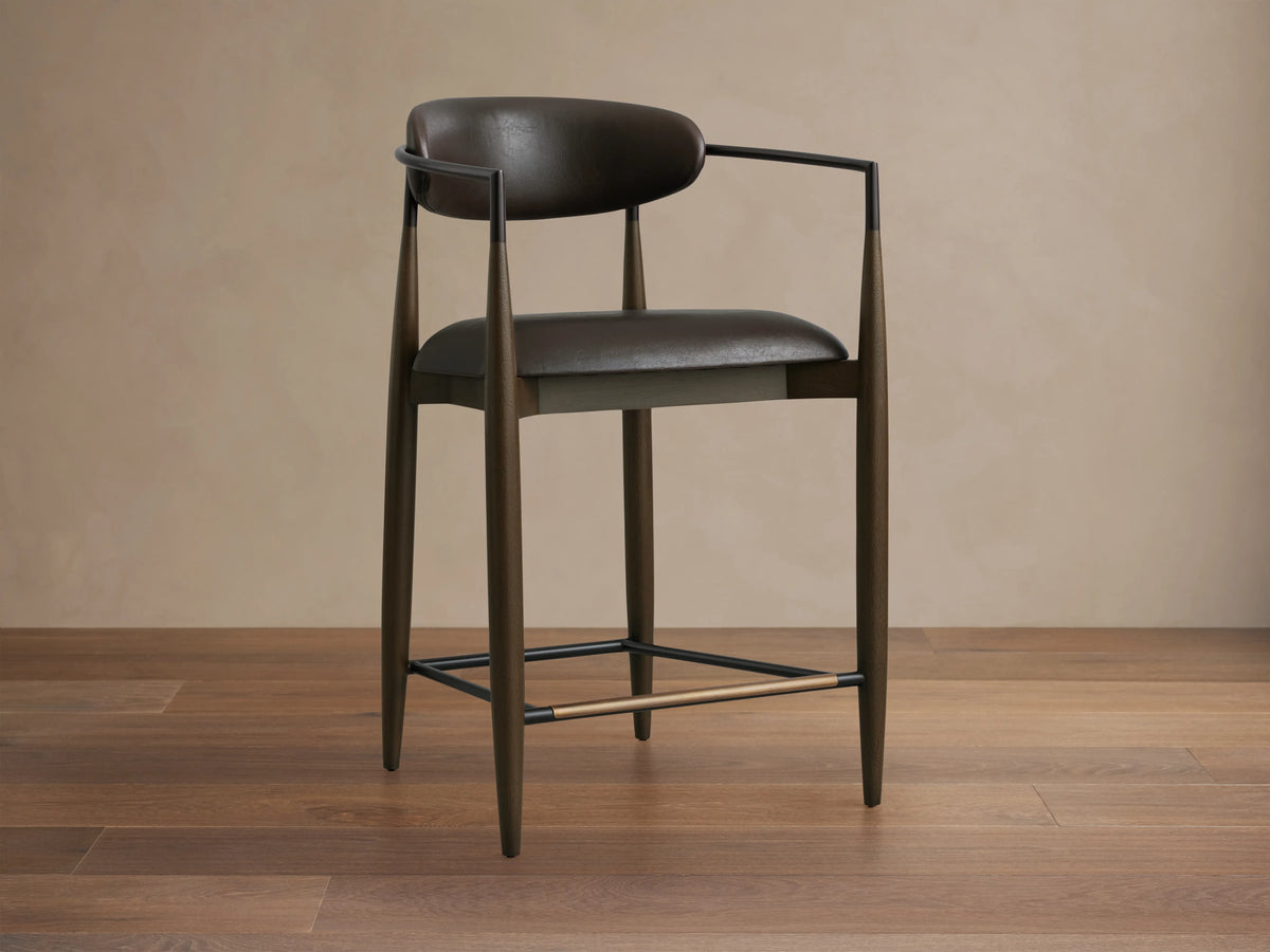 Jagger Faux Leather Stool featuring dark brown faux leather seat and backrest, sleek metal frame, and footrest.