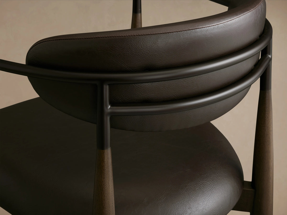Jagger Faux Leather Stool with a brown seat and backrest, slim black metal frame, and tapered legs on a wooden floor.