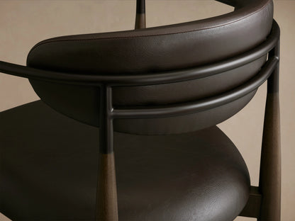Jagger Faux Leather Stool with a brown seat and backrest, slim black metal frame, and tapered legs on a wooden floor.