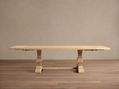 Light natural wood Kensington Dining Table, rectangular top, two chunky carved pedestal bases, shown straight on a wood floor.